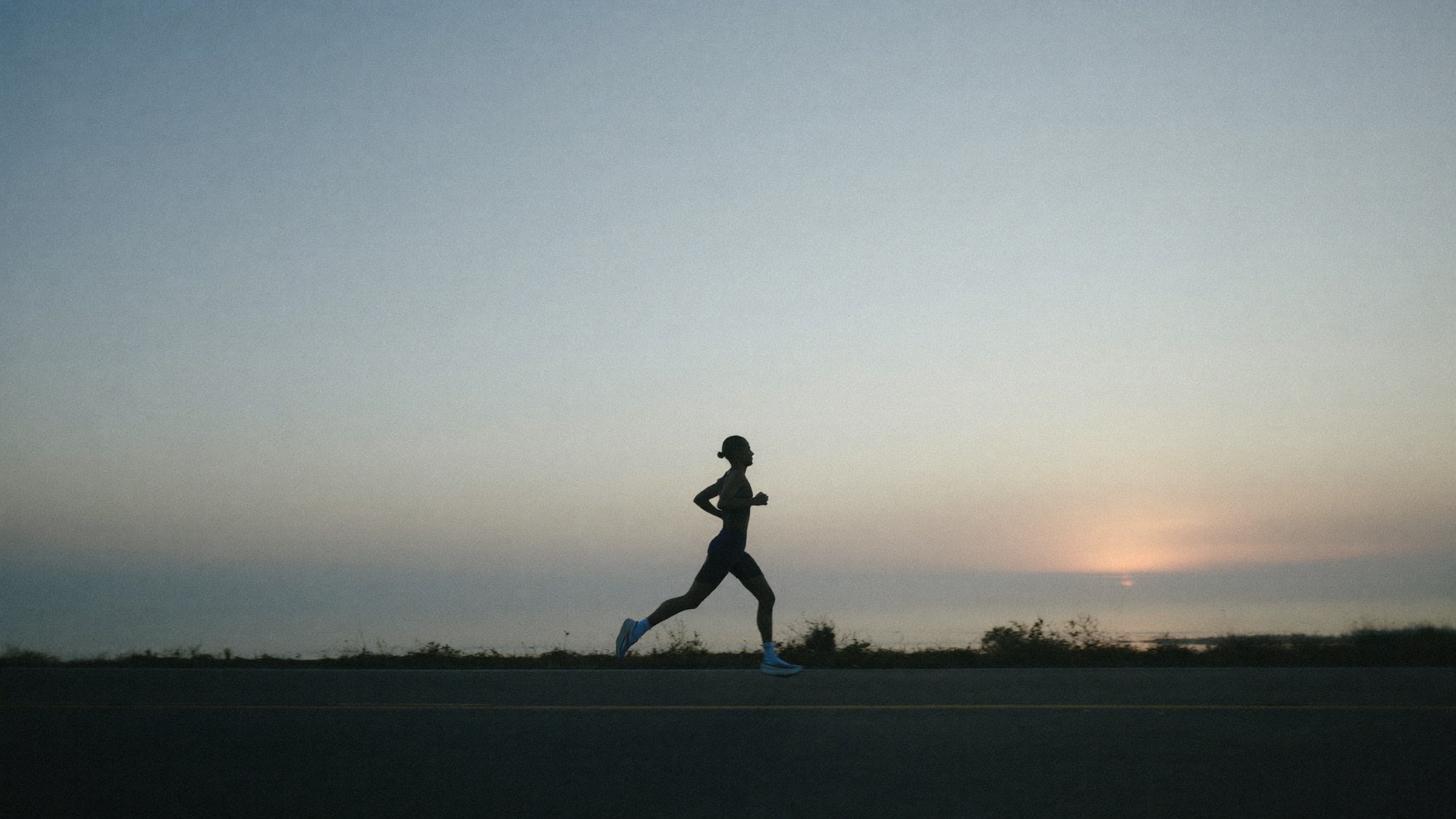A runner on a coastal road at dawn
