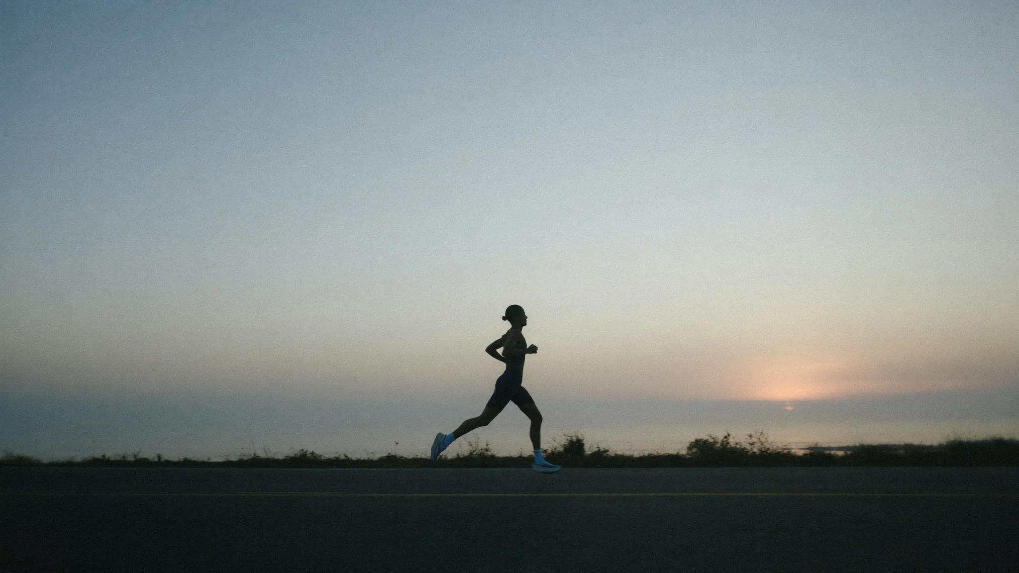 A runner on a coastal road at dawn